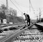 153403 Afbeelding van een wegwerker van N.S. tijdens het smeren van een wissel op het emplacement van het N.S.-station ...